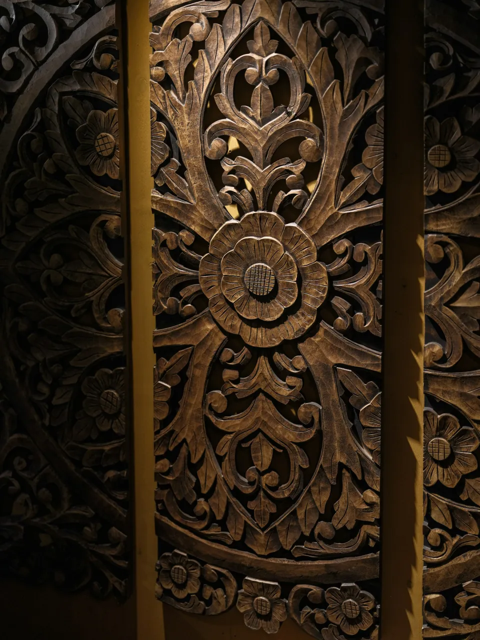 Close-up of a wooden door with a detailed floral mandala carving