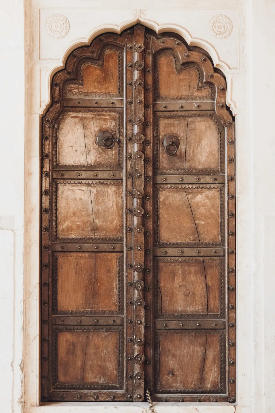Tall carved wooden door with an arched top and metal studs