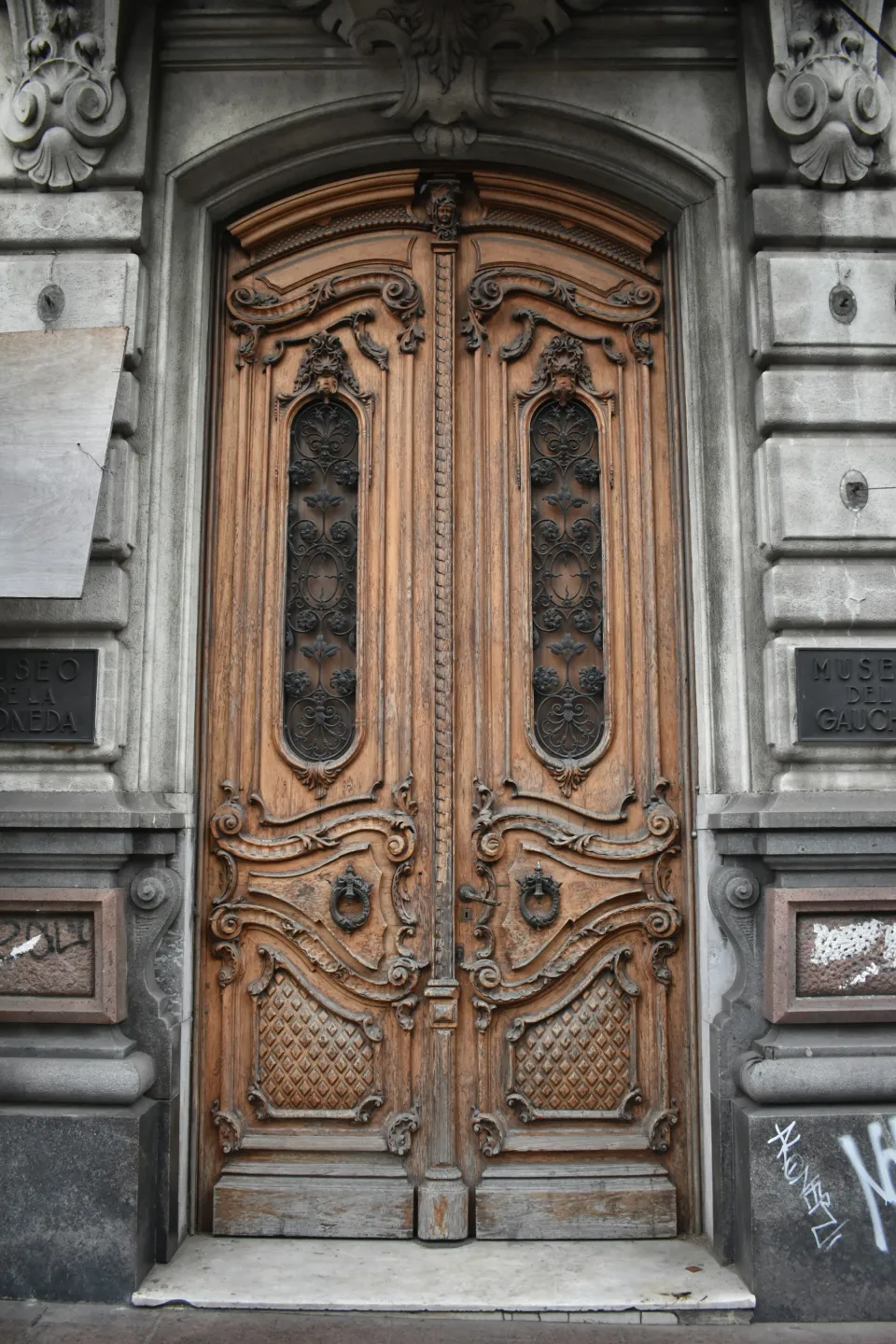 Arched carved wooden double door set in a stone facade