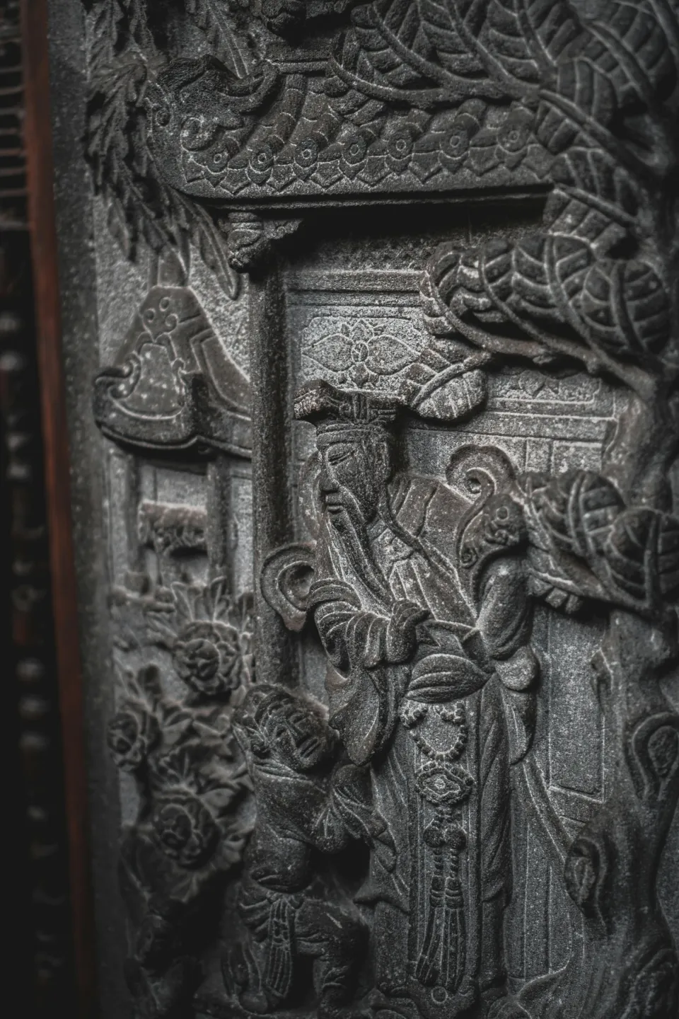 Dark carved wooden door with relief figures and foliage